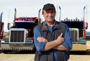 truck driver in front of two commercial truck vehicles