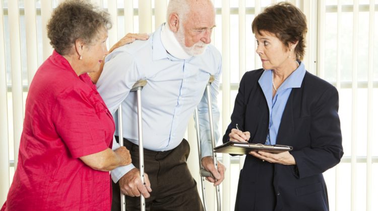 injured elderly man on crutches with his wife and a lawyer
