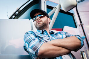man crossing his arms leaning his back on an 18 wheelers truck