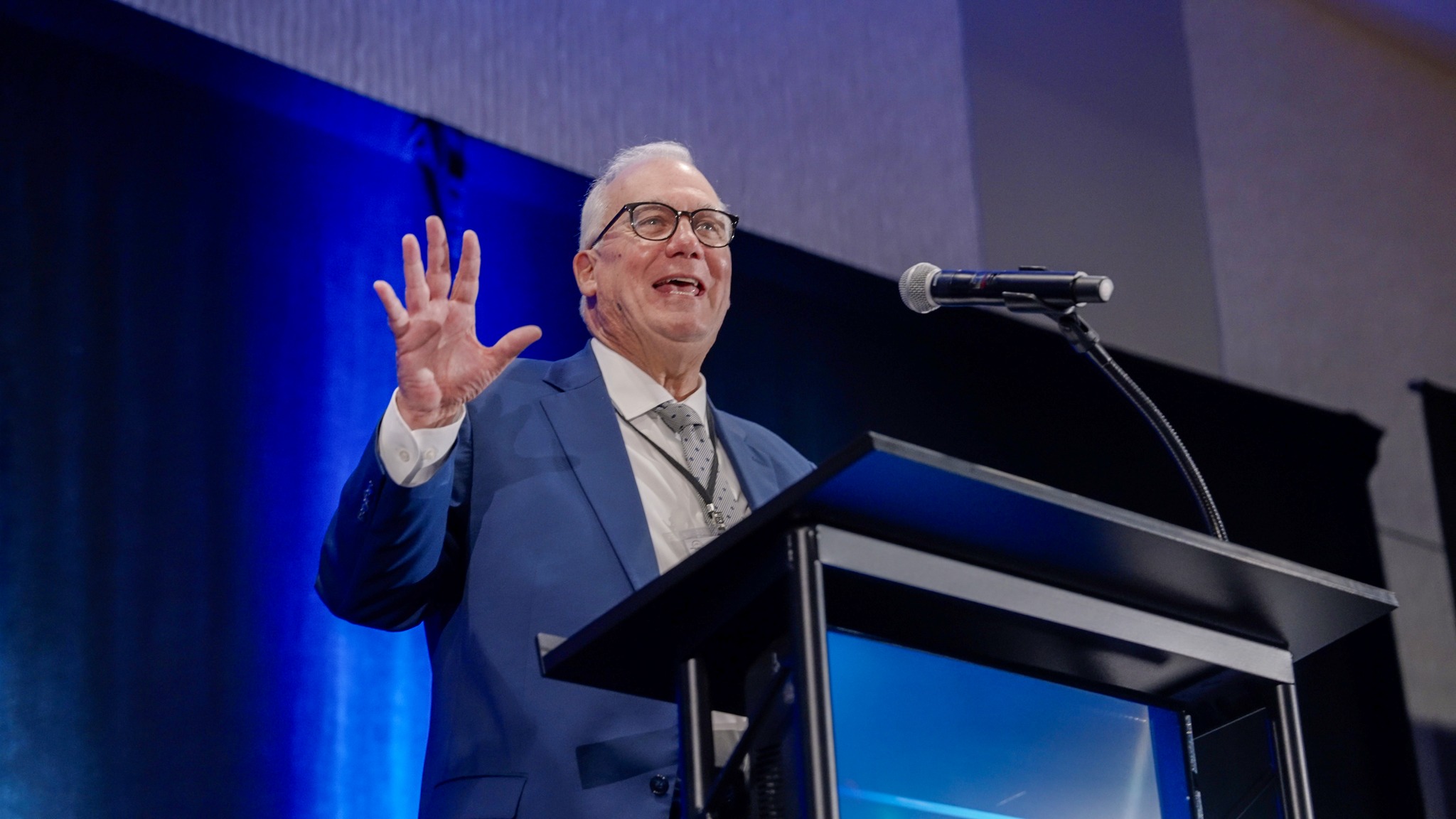 David Craig standing in front of podium speaking into microphone