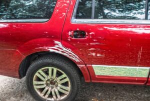 Bright cherry red pickup truck that's been sideswiped by white vehicle.