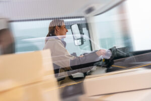 Delivery driver driving van with parcels on seat outside warehouse with motion blur