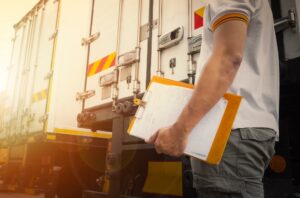 man holding a checklist behind a truck